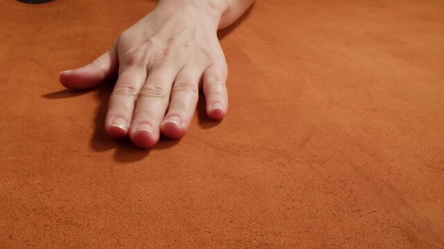 Nubuck texture with woman hand touching, close up of red, orange and green suede leather surface, soft natural nubuck material sample in leather shop and factory