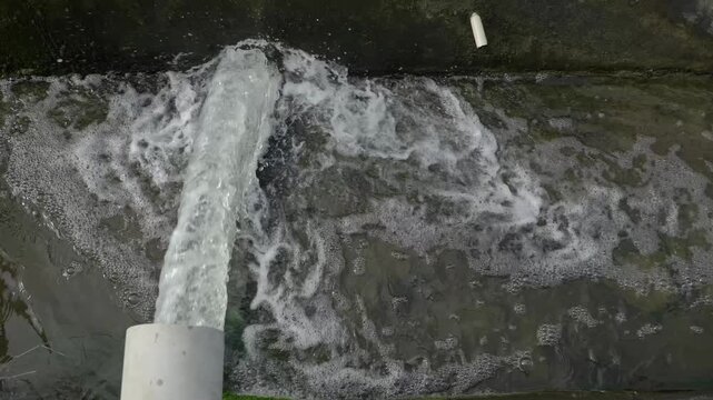 Wastewater Discharge from Industrial Drain Pipe into Sewer System (video 4K)