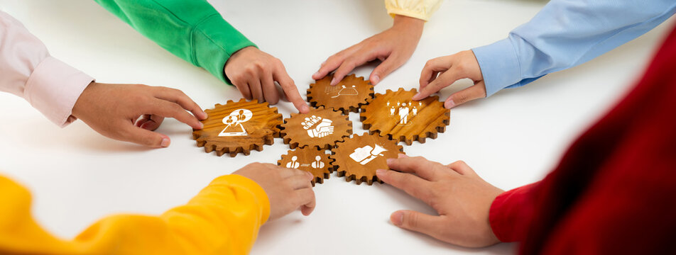 A diverse group collaborates around wooden gears, symbolizing teamwork and innovation in strategy development for business success and effective planning. Amity