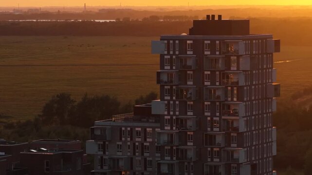 Aerial drone view of a residential tower overlooking the meadows of Amager Common at sunset, Copenhagen, Denmark.