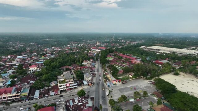 Aerial view of a small town with a main road running through residential areas and buildings under a daytime sky. Urban landscape, transportation, and community travel concept.