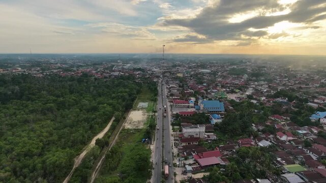 High-angle perspective tracking along a central road dividing a compact community townscape with local buildings and houses. Countryside urban development and lifestyle.