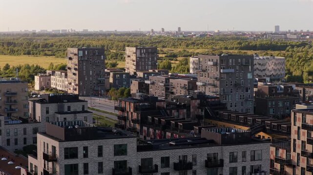 Aerial drone view of residential blocks of Orestad beside the green meadows of Naturpark Amager, Copenhagen, Denmark.
