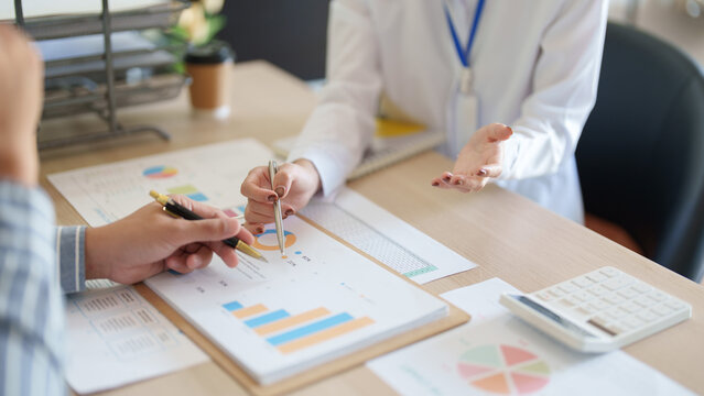 Asian business team analyzing financial charts on desk for corporate strategy