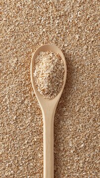 Wooden spoon with organic oat bran and a textured grain background
