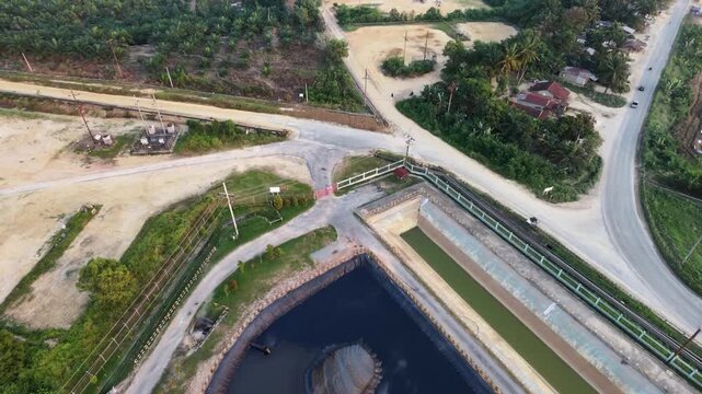 Aerial view of an industrial wastewater treatment facility with storage ponds and processing tanks near an industrial plant under a clear sky. Environmental management and industry concept.