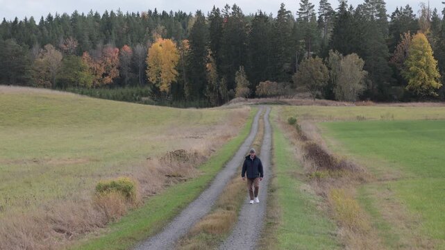 Linkoping, Sweden A man walks on a country path with autumn foliage.  
