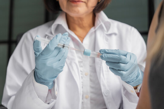 Mature Asian doctor use syringe to draw the medicine from the vial