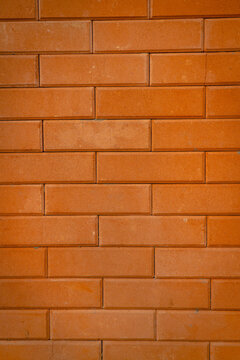 Close-up of an orange-brown brick surface with rectangular units, visible mortar joints, and a repeating horizontal arrangement.