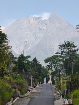 Scenic Rural Village Lane Framed By Tropical Greenery With Mount Merapi Volcano Rising In Central Java Indonesia