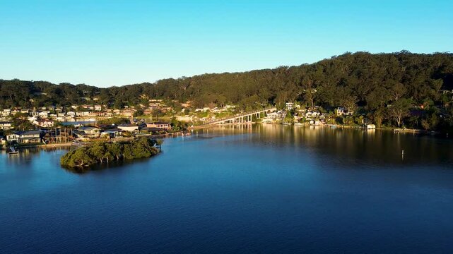 Drone aerial landscape of St Huberts Island Bridge over Brisbane Water river inlet surrounded by residential neighborhood housing and bushland trees on headland at Daleys Point Central Coast Australia