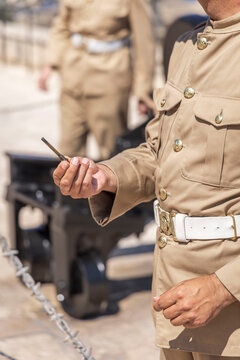 Close-up of a ceremonial military guard in khaki uniform holding a historic cannon friction primer.