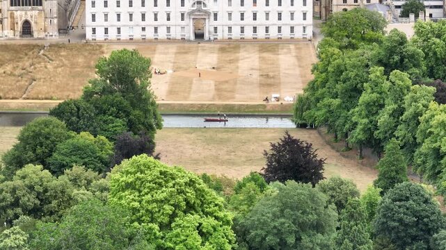 Aerial view of the River Cam college buildings and leafy gardens in Cambridge England with a punt on the river