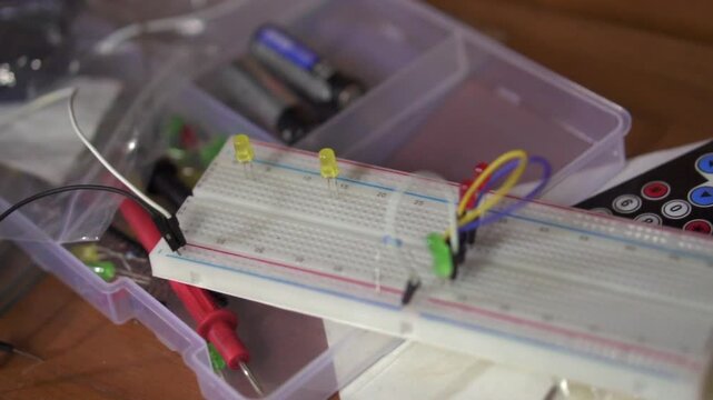 Breadboard with two yellow LEDs and connected wires in an electronics workspace.