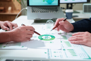 Business professionals collaborating on ESG sustainability reports, analyzing environmental...