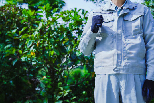 自然の背景で拳を握る作業服の男性