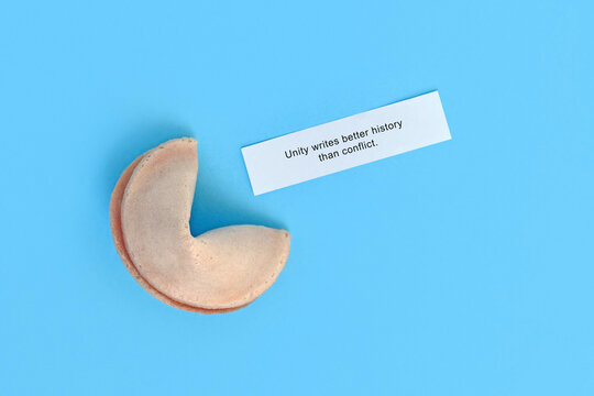 Fortune cookie with text saying 'Unity writes better history than conflict" on blue background