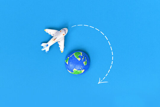 Top view of airplane and world globe with directional arrows on blue background. World travel and global tourism concept