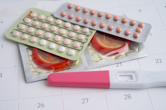 Pregnancy test and condom for female on calendar, ovulation day.