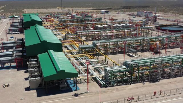 Aerial view of the Fort&iacute;n de Piedra gas processing plant in the Vaca Muerta shale reserve, Neuqu&eacute;n, Argentina. Green roofs; yellow, white, and red pipes. 4K.