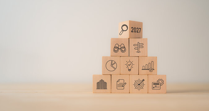 2027 Business Outlook. Strategic Planning, Market Analysis and Future Growth. Wooden blocks stacked with 2027 and business icons. Market research, strategic planning, financial analysis, innovation.
