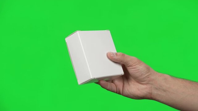 Hand holding and turning blank white box on green screen background