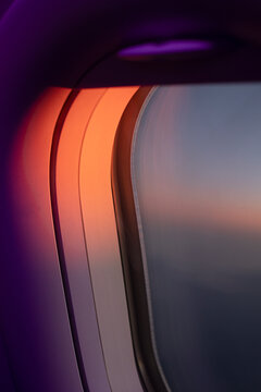 Abstract close-up of airplane window glowing in red and violet light