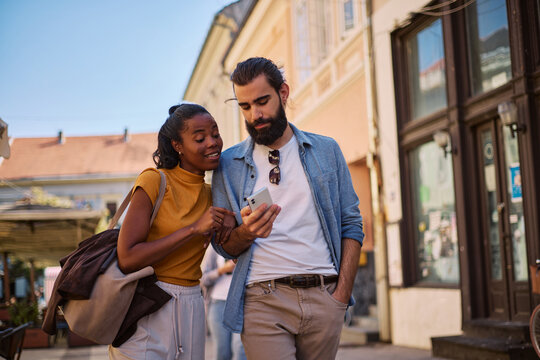 Diverse couple exploring city street using smartphone