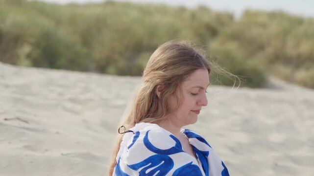 Woman adjusting her dress on sandy dunes by the sea