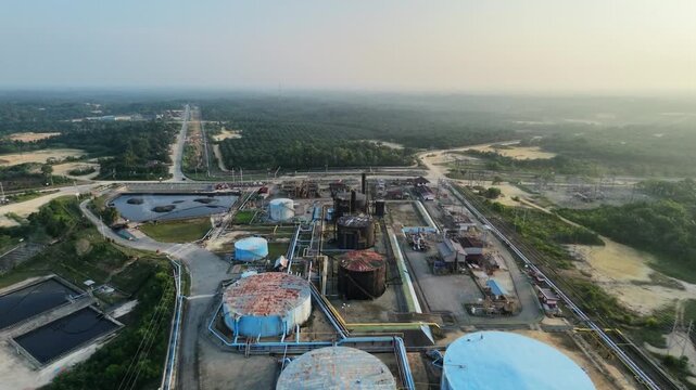 aerial landscape of a crude oil and natural gas processing plant with storage silos and pipeline networks at sunset. Industrial economy, power generation, and fuel supply.