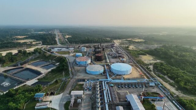 aerial landscape of a crude oil and natural gas processing plant with storage silos and pipeline networks at sunset. Industrial economy, power generation, and fuel supply.