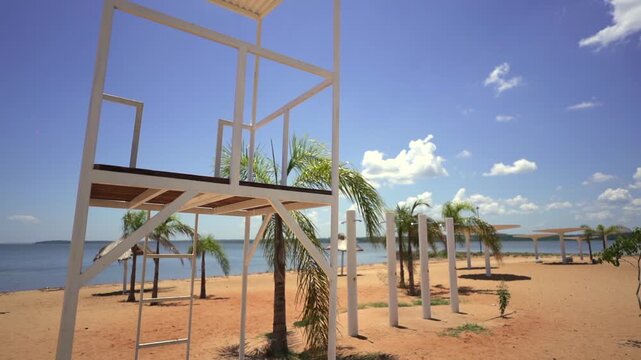 Bright sunny day illuminates a white lifeguard tower and palm trees along the Parana River in Ituzaingo, Corrientes Province.