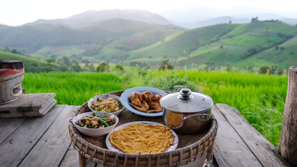 Naklejka premium A set of Thai traditional dining table with rice terrace and mountain views