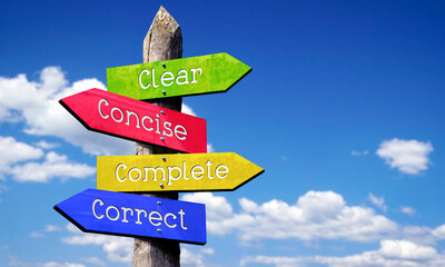 Clear, concise, complete, correct - wooden signpost with four arrows, sky with clouds © PX Media