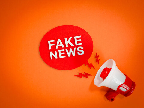 Megaphone beside bold fake news message in red speech bubble on orange background. Misinformation amplification, disinformation spread, media manipulation, viral content and digital trust risks.