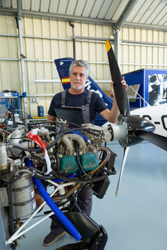 Mechanic inspecting light aircraft engine and propeller