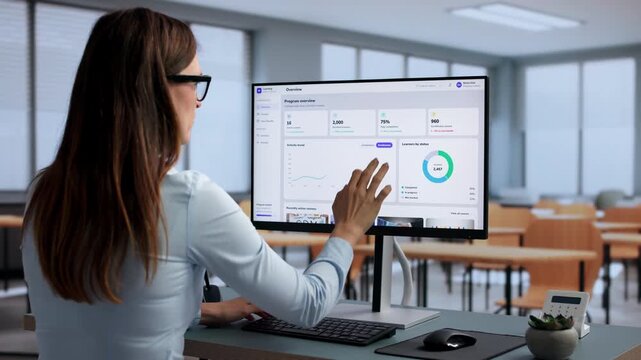 Corporate Trainer Reviews Employee Progress Charts On Computer