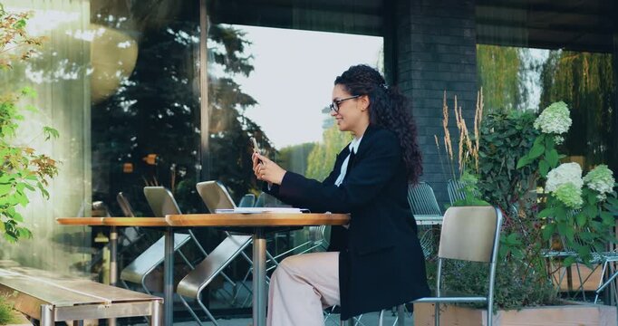 Business woman taking part in an online business meeting on a smartphone outdoors, remote work and digital communication concept