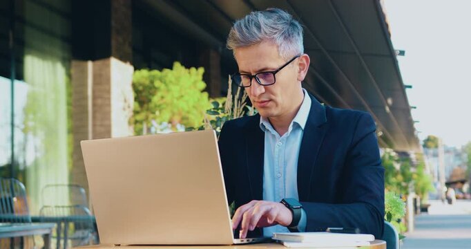Overworked businessman looking at his watch no time is late, checking time near office place using laptop working typing message business man or lawyer in suit looking at expensive watch outdoors.