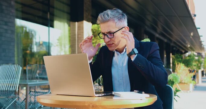 Business man using laptop and reading bad news or disappointed with mobile phone app while standing office building background, outdoors