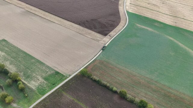 Aerial view of agricultural fields with contrasting soil colors and a narrow road in Hombourg, Grand Est, France.