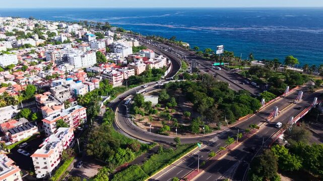 An aerial drone shot panning from Puente Juan Carlos along Avenida Las Am&eacute;ricas toward the open Caribbean Sea in Santo Domingo Este