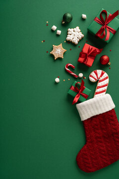 Merry Christmas and Happy New Year stocking with gifts, cookies, candy and ornaments on vertical green background