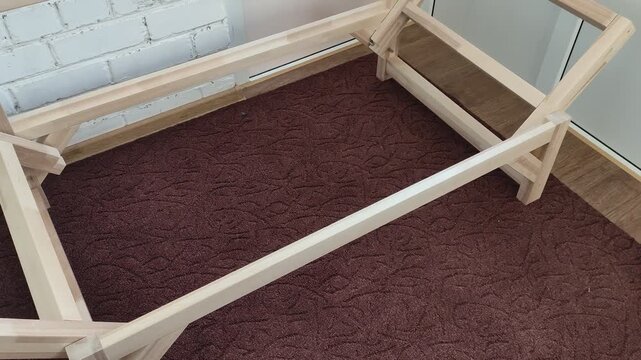 Wooden frame of a futon sofa bed without mattress in a bright room, assembly stage