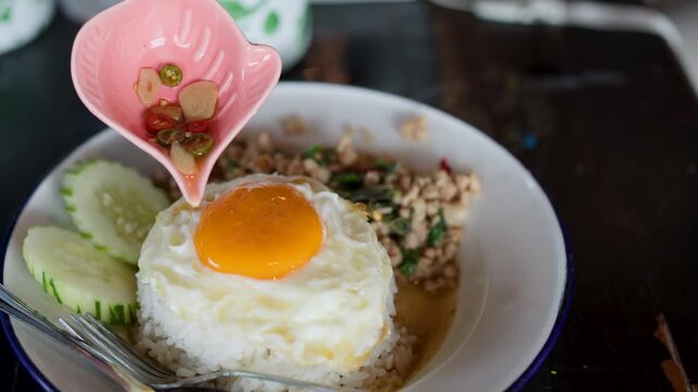 Pouring Chili Fish Sauce Over Thai Pad Krapow With Fried Egg
