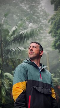 Man exploring rainforest looking up at dense foliage