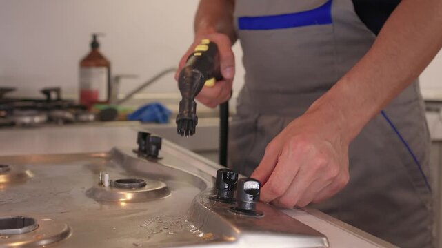 Handheld steam cleaner on stove top, powerful steam loosening burnt grease from stainless surface, closeup of nozzle and hand motion, countertop background, satisfying deep clean