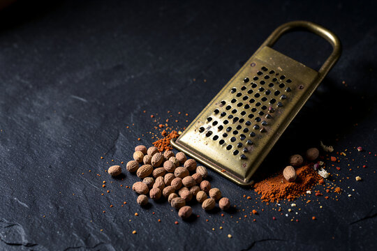 Whole Nutmeg Pods And Brass Grater On Dark Slate Macro Flat Lay