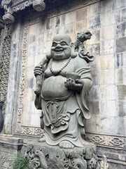 Fototapeta premium Smiling Buddha stone carving on an ornate temple wall in Chongqing, China