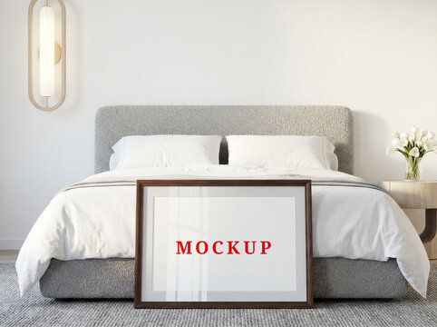 Empty poster frame mockup above bed in minimalist bedroom interior design.